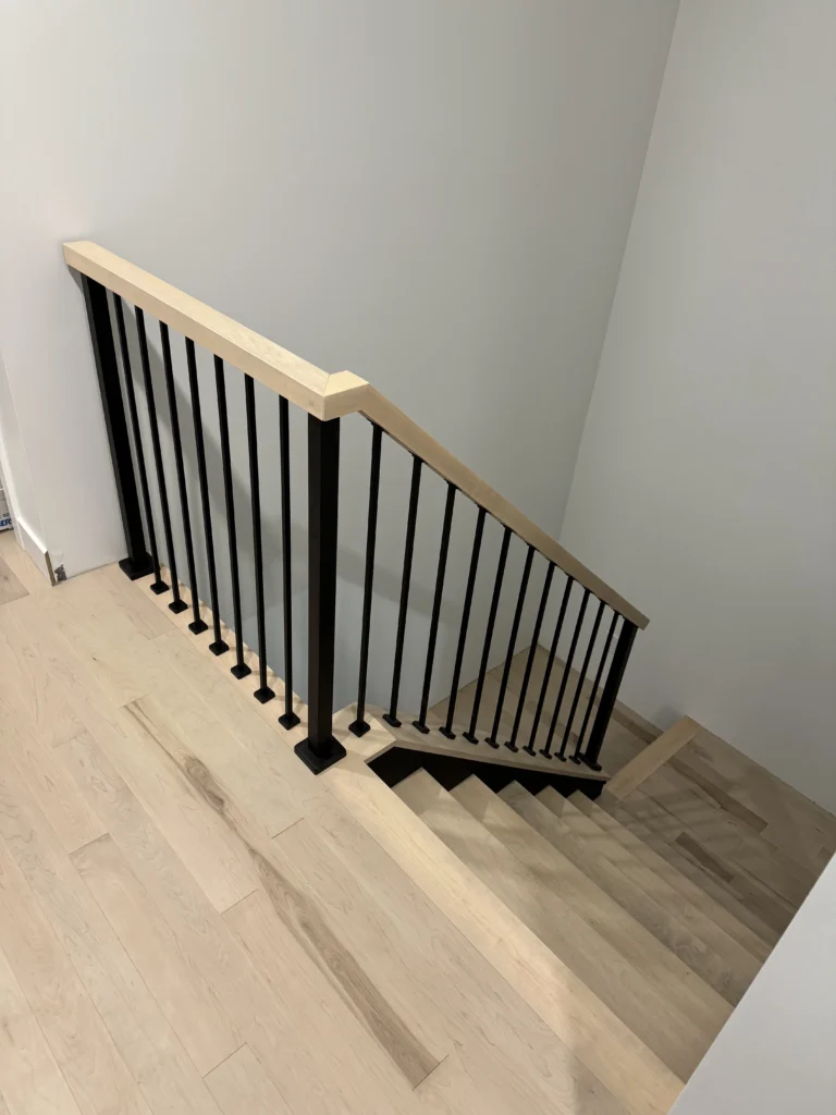 Palier de l'escalier en érable avec barreaux métalliques noirs