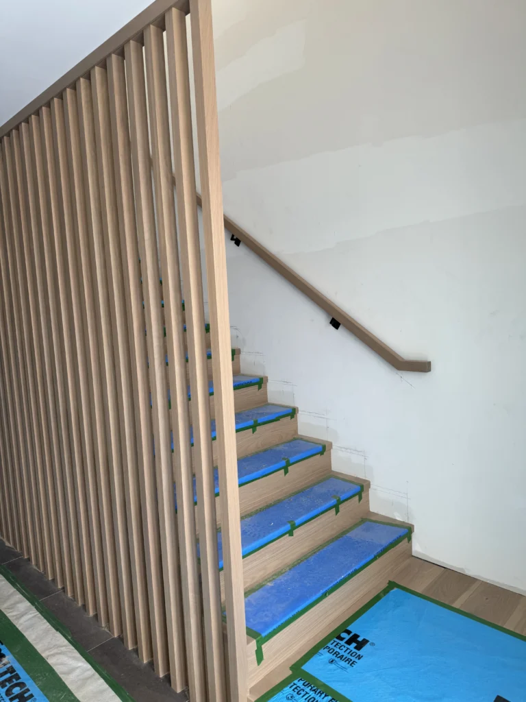 Escalier droit derrière un claustra de bois