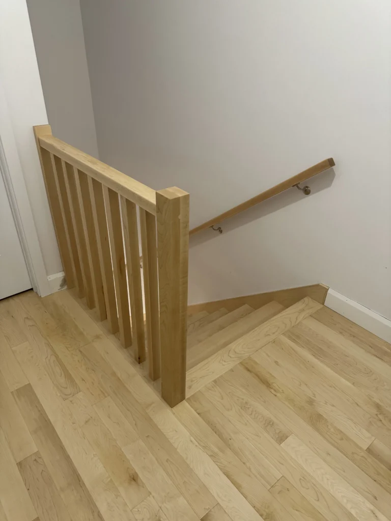 Escalier droit en érable naturel à barreaux de bois et marche de départ arrondie