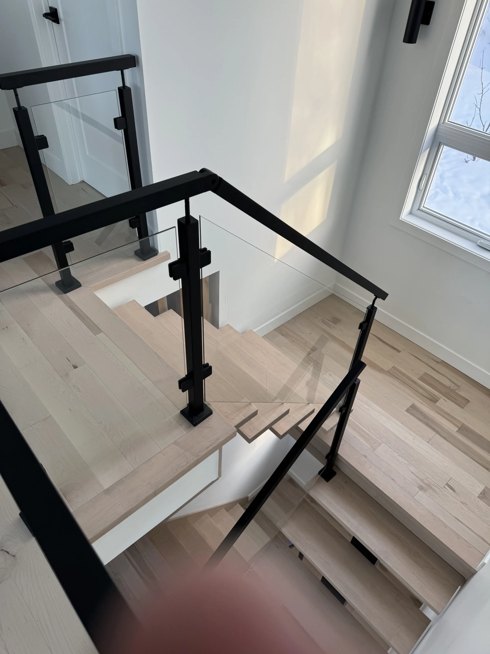 Escalier tournant à garde-corps de verre et poteaux métalliques noirs — vue principale