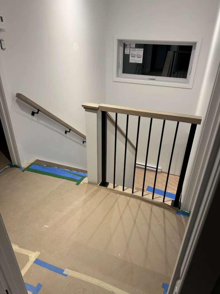 Palier de l'escalier en chêne blanc avec barreaux métalliques noirs