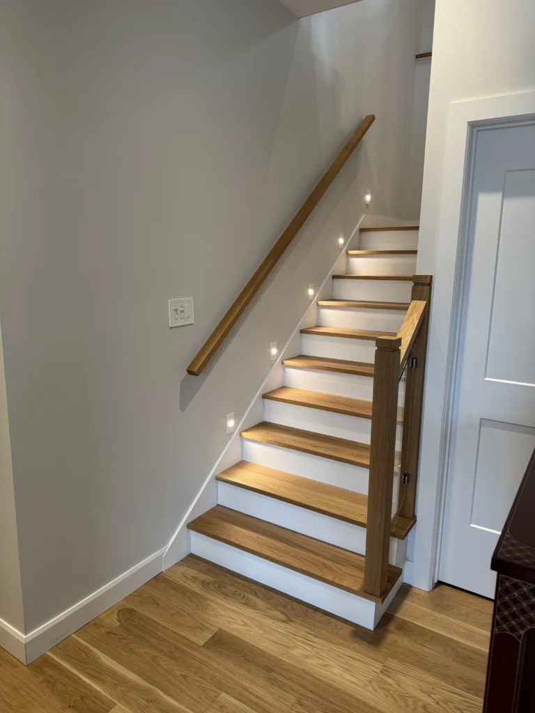 Escalier tournant en chêne blanc à contremarches blanches et garde-corps de verre