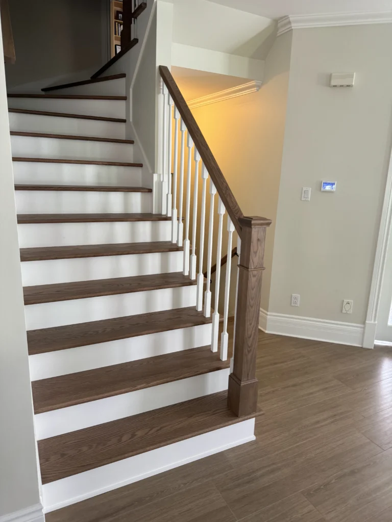 Escalier tournant en bois franc teinté brun à barreaux tournés blancs