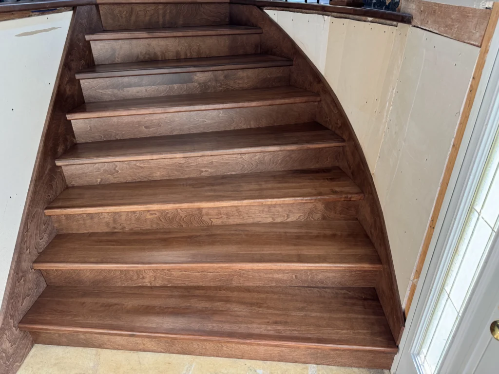 Escalier tournant en bois teinté foncé à barreaux de fer forgé