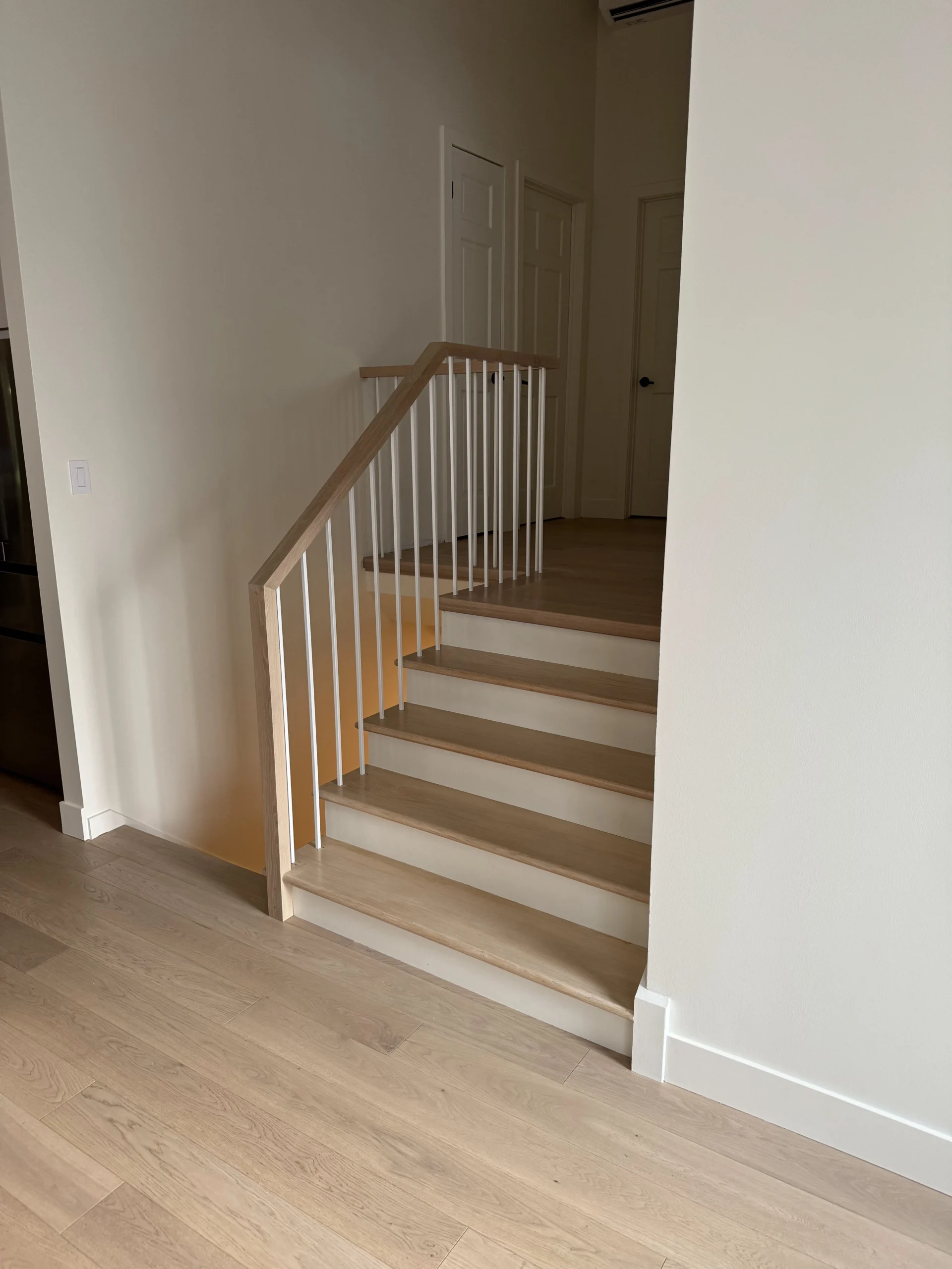 Escalier tournant en chêne à barreaux blancs et main courante de chêne — vue principale