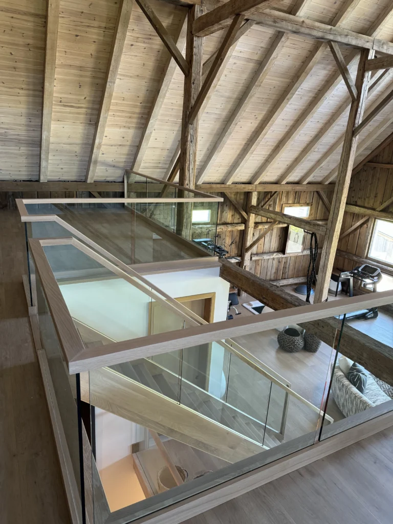 Mezzanine à garde-corps de verre sous charpente de bois apparente