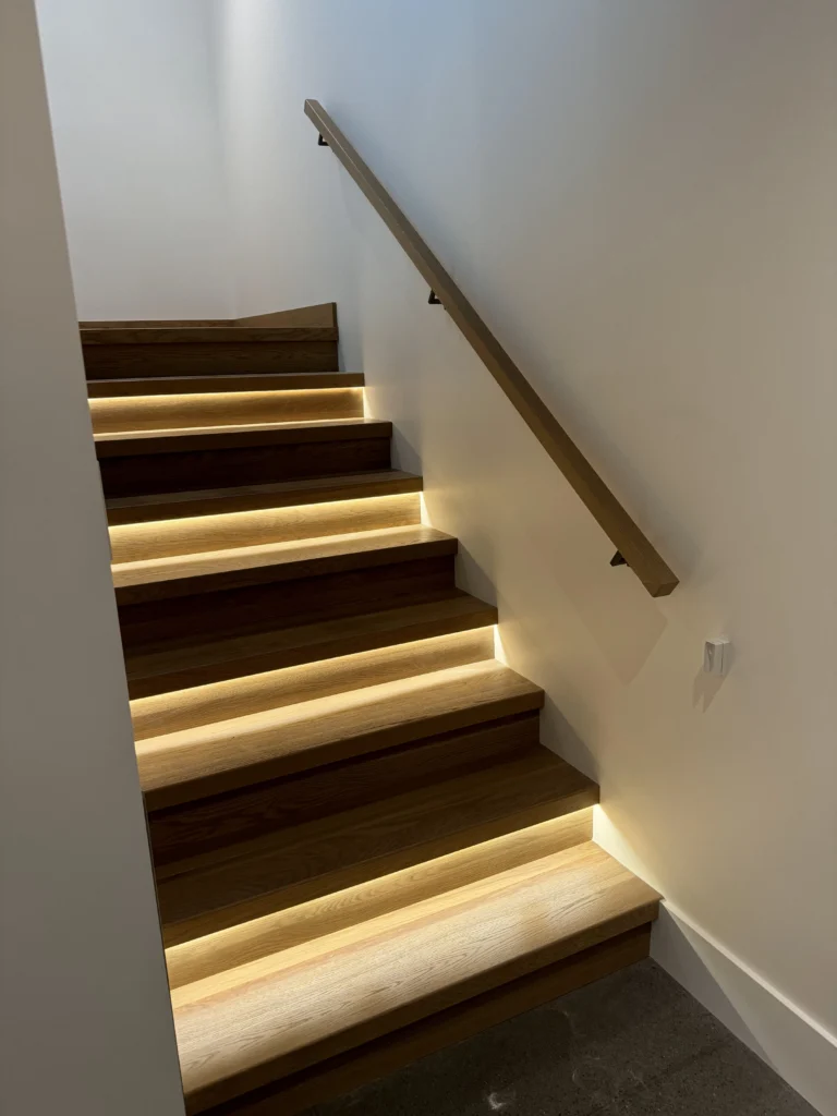 Marches de chêne soulignées d'un ruban lumineux, main courante de bois
