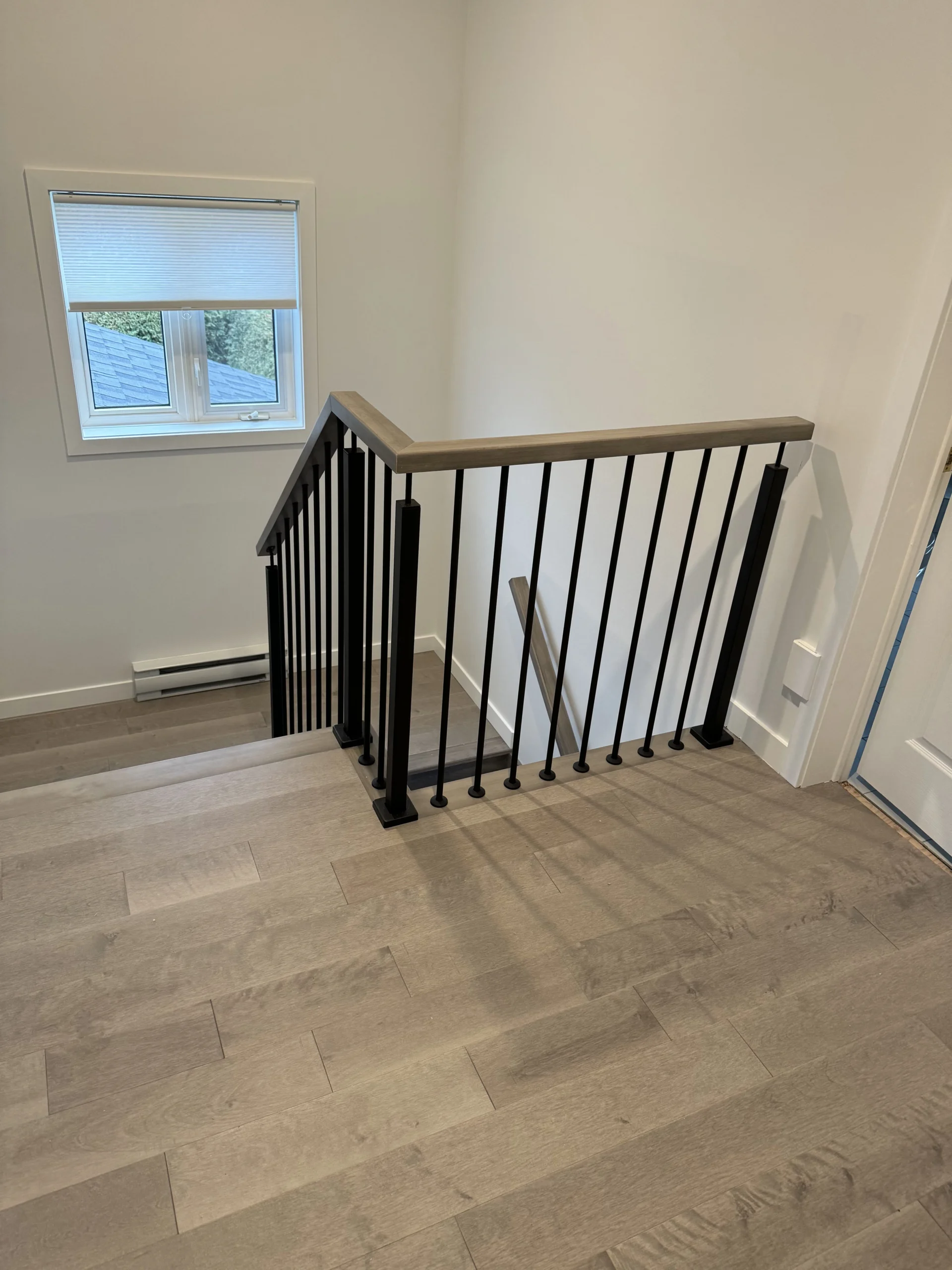 Escalier d&rsquo;entrée à barreaux d&rsquo;acier noir et plancher teinté gris — vue principale