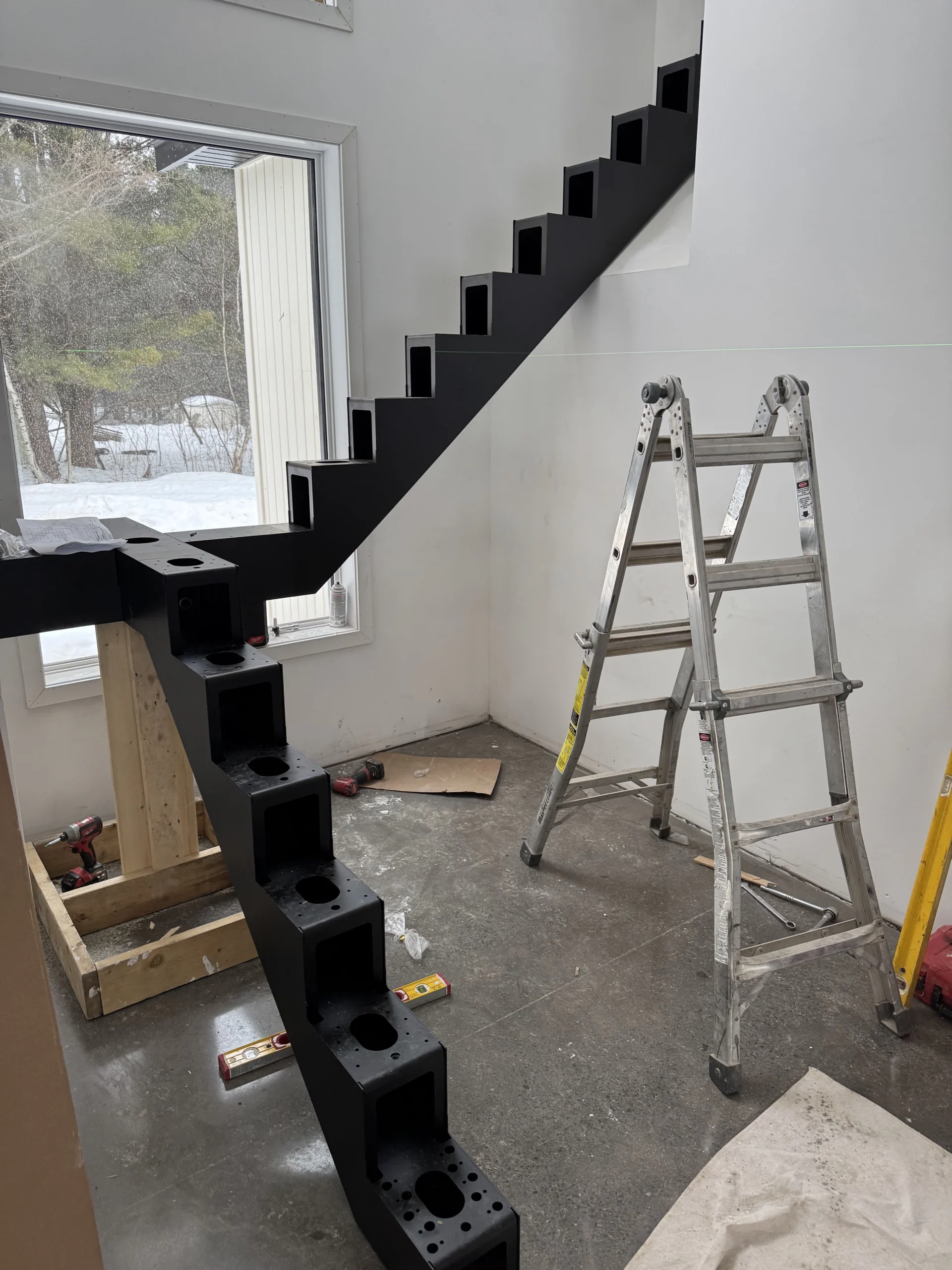 Escalier à limon central d&rsquo;acier noir en cours d&rsquo;installation — vue principale