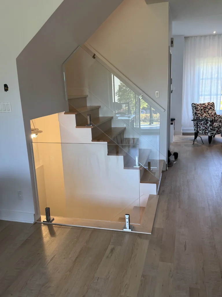 Escalier suspendu à marches de bois clair et garde-corps de verre