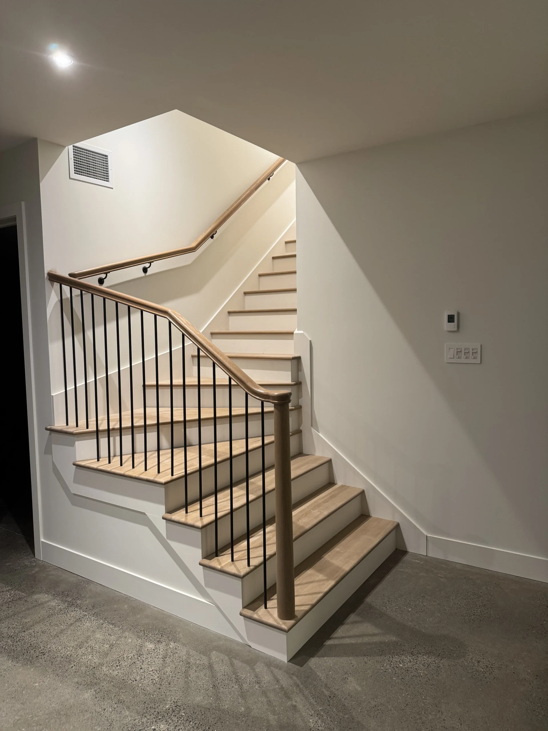 Escalier tournant à barreaux d&rsquo;acier noir et poteau de bois tourné — vue principale