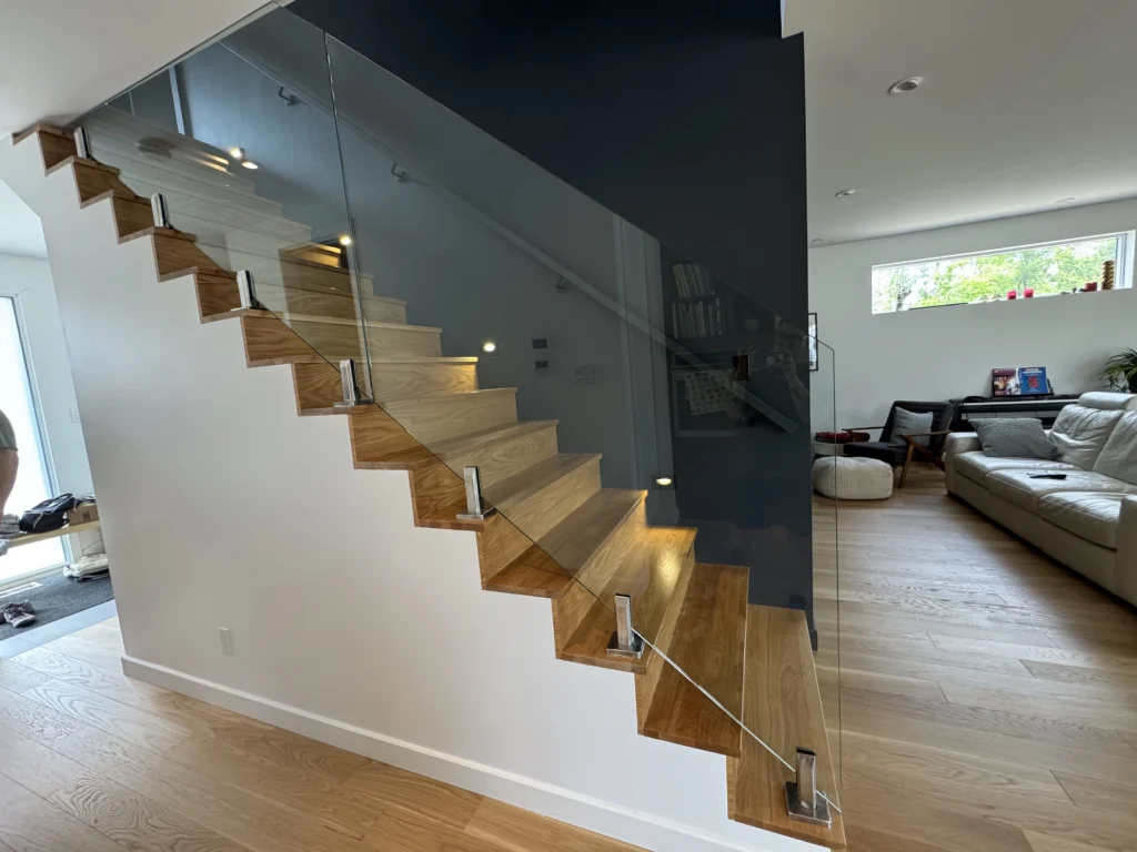 Escalier suspendu en chêne blanc à garde-corps de verre et mur d&rsquo;accent