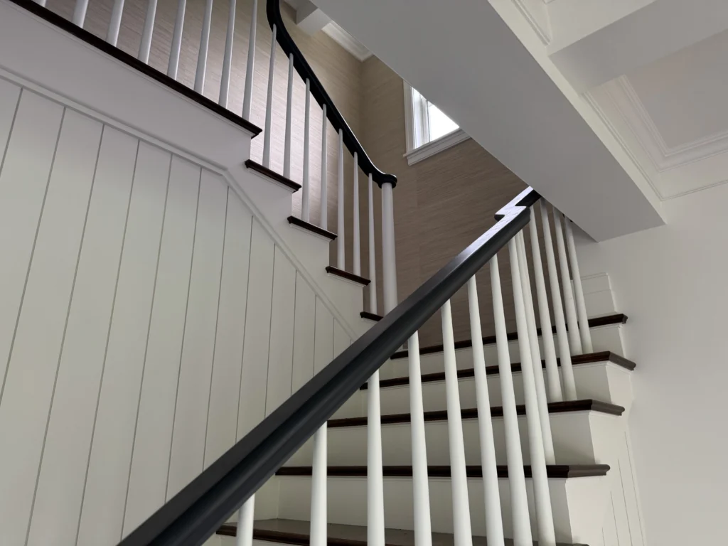 Escalier tournant classique à barreaux blancs et main courante foncée