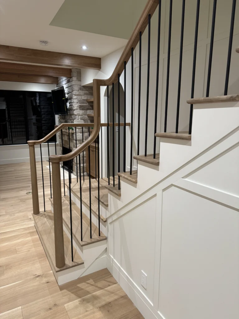 Escalier tournant à barreaux d&rsquo;acier noir et boiserie sur mur de pierre
