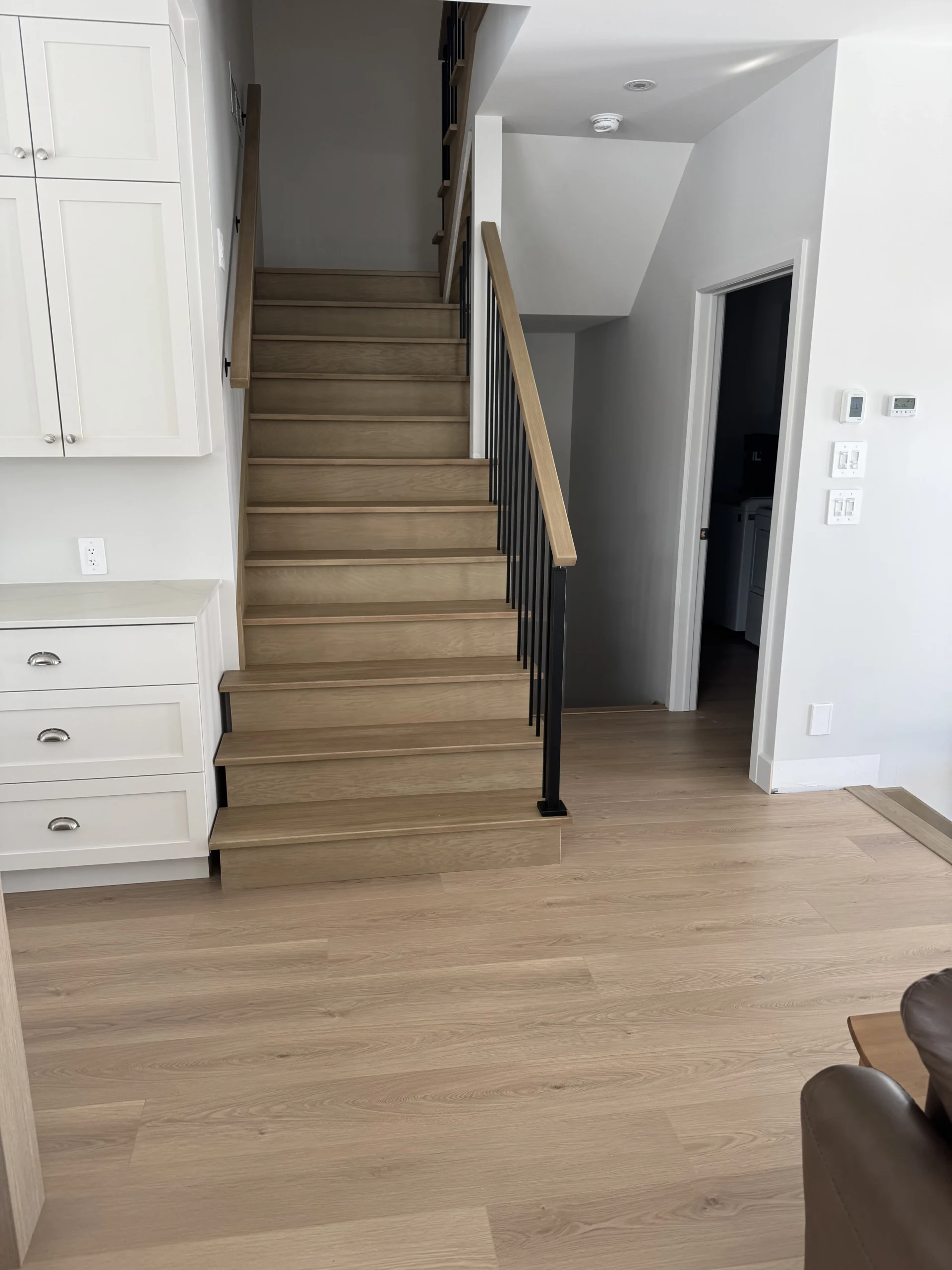 Escalier droit en chêne blanc à barreaux d&rsquo;acier noir et cuisine attenante — vue principale
