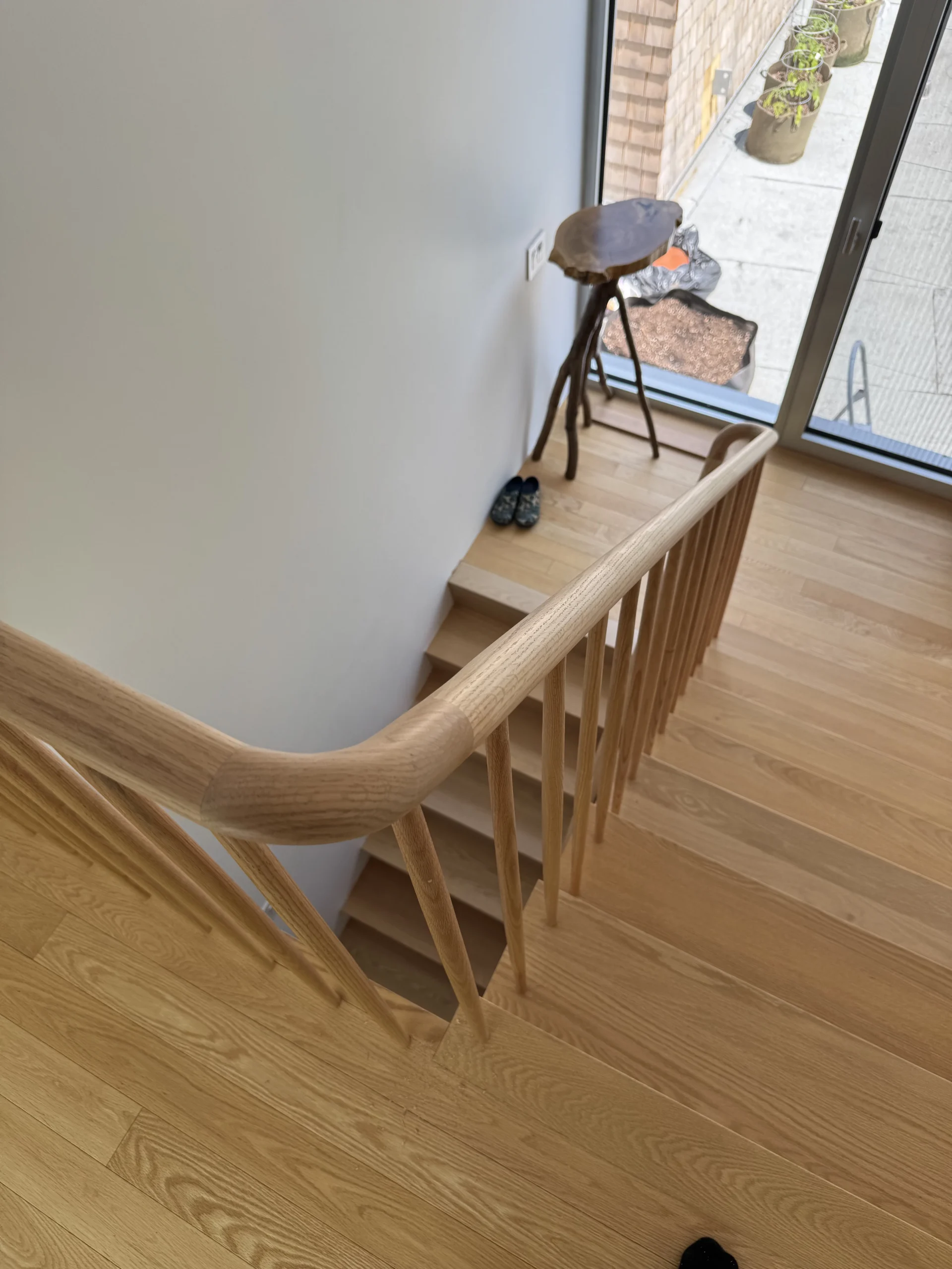 Escalier tournant en frêne blond à barreaux de bois et main courante galbée — vue principale