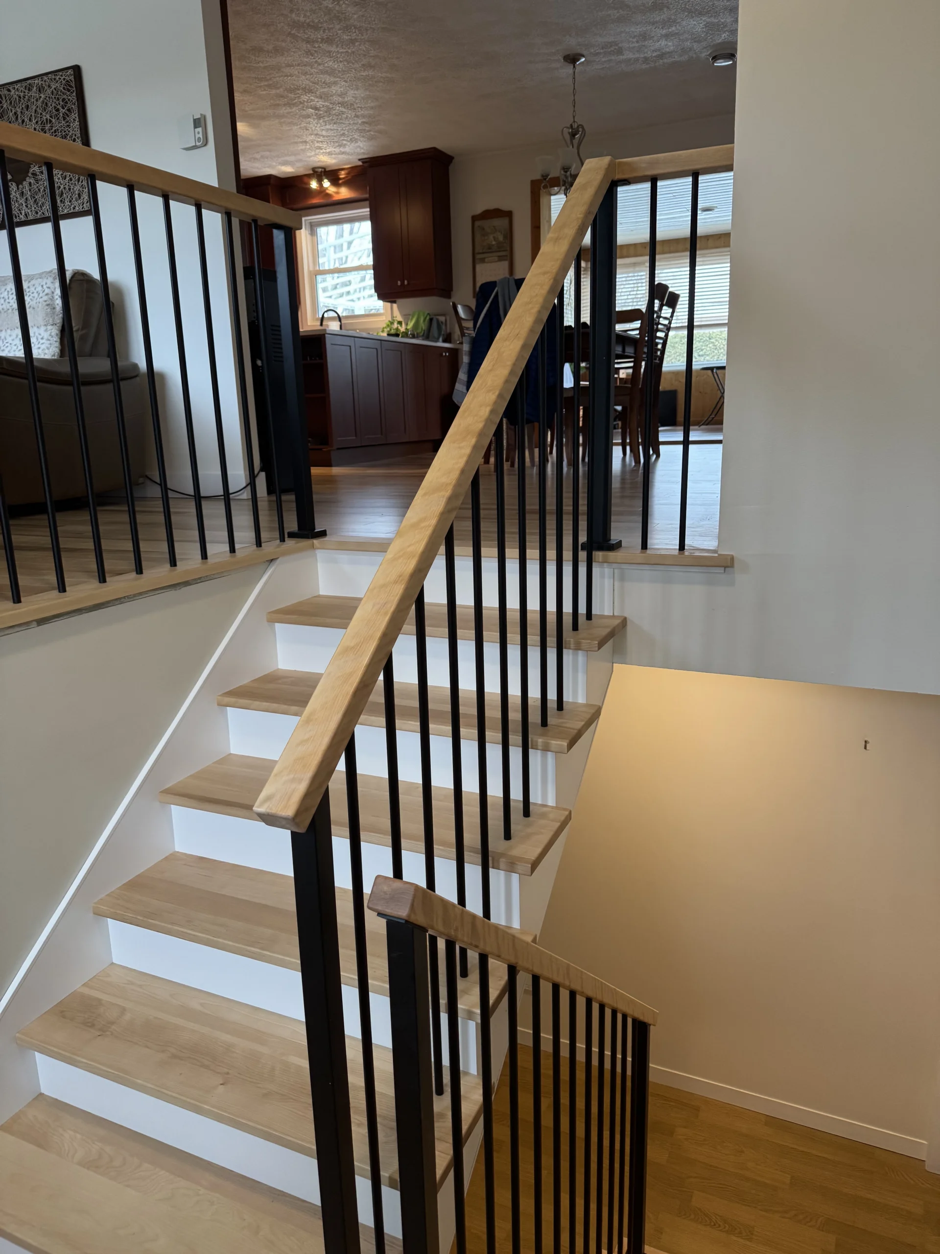 Rénovation d&rsquo;escalier à paliers, barreaux métalliques noirs et marches de bois blond — vue principale