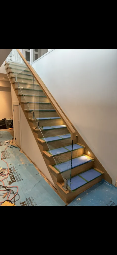 Escalier droit en chêne blond à garde-corps de verre sur attaches d'inox, en fin de chantier, à Longueuil