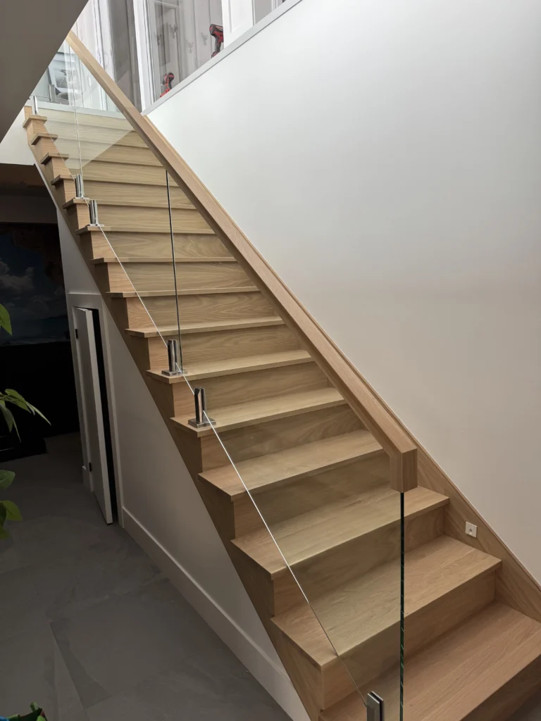 Escalier droit en chêne blond à garde-corps de verre et main courante de bois