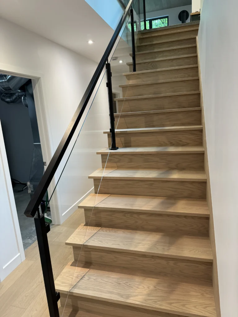 Escalier droit en chêne blond à garde-corps de verre et métal noir