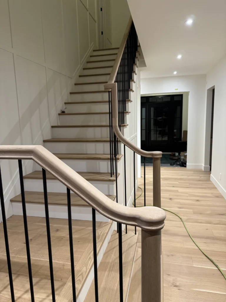 Escalier tournant à main courante galbée et barreaux métalliques noirs