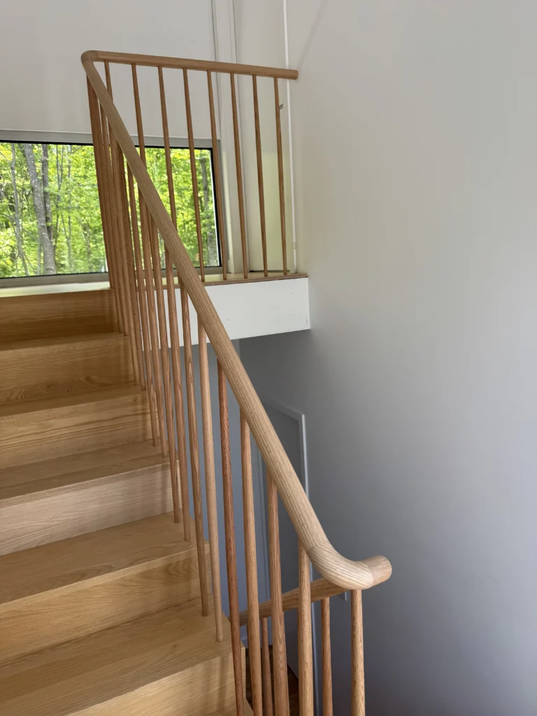 Escalier tournant en frêne à barreaux ronds et main courante sculptée