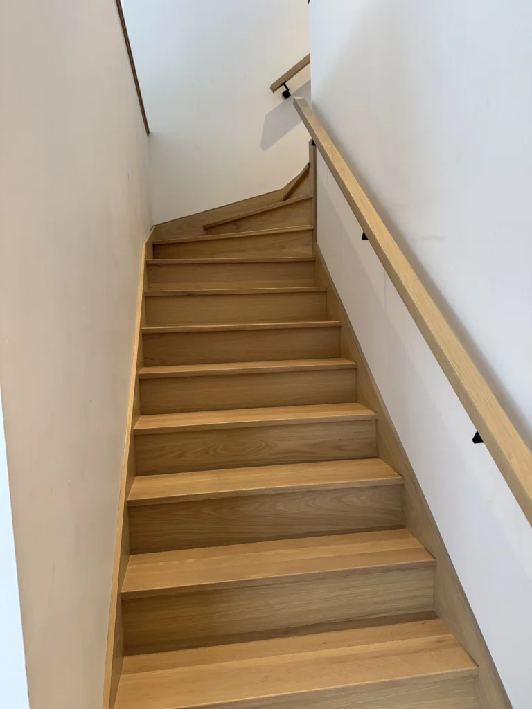 Escalier tournant en chêne blanc entre deux murs à marches rayonnantes