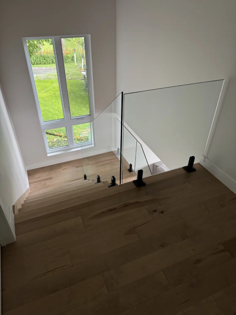 Escalier droit en érable brun chaud à garde-corps de verre sans cadre