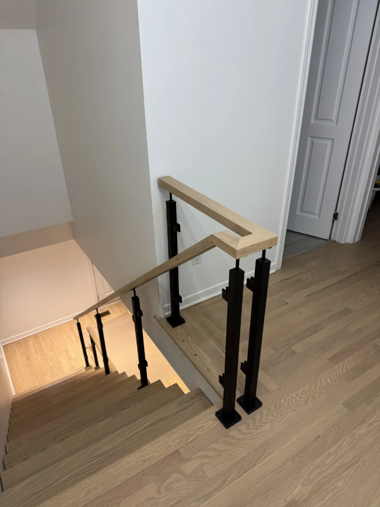 Escalier tournant en chêne blond, poteaux noirs et main courante bois