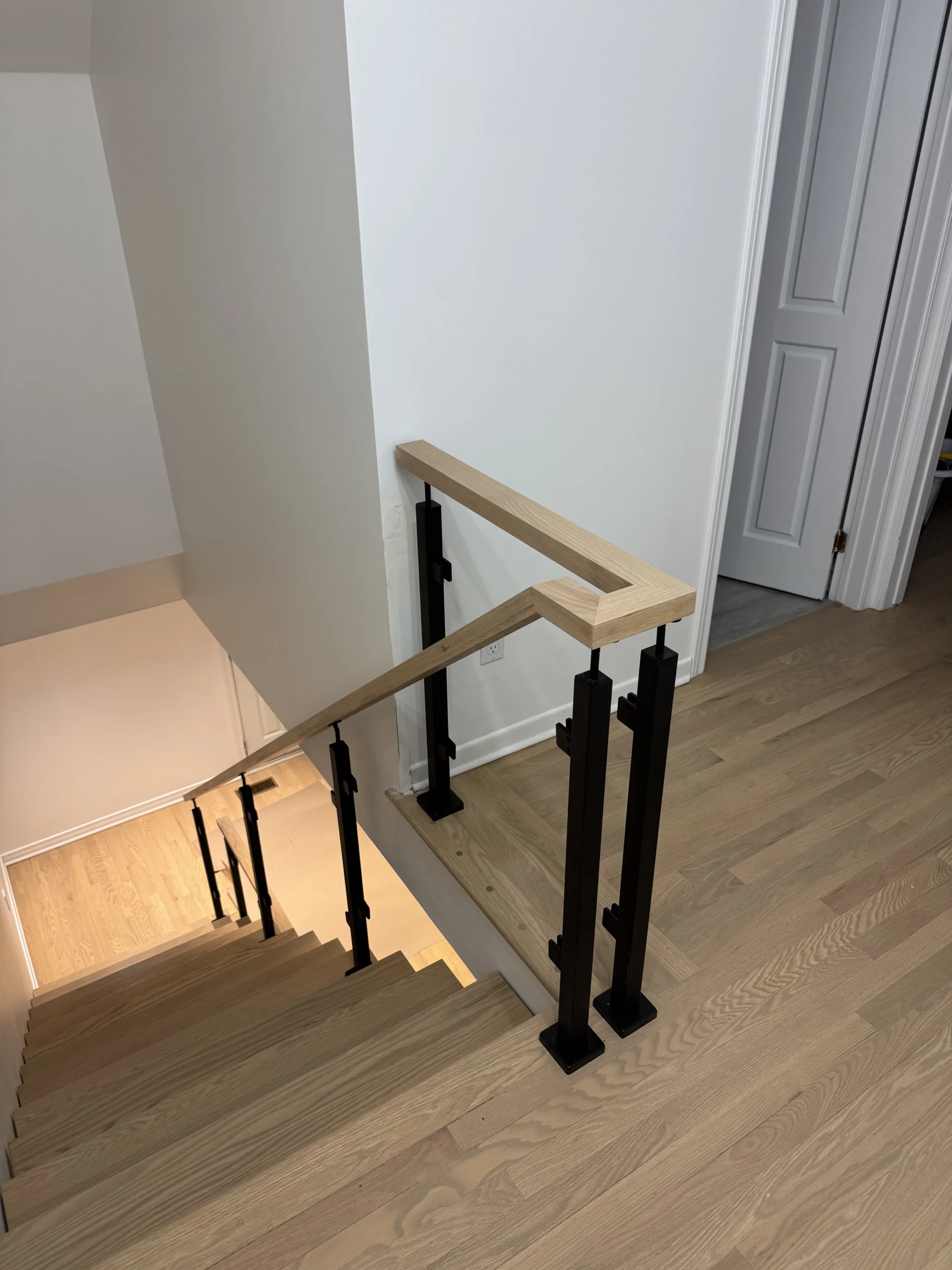 Escalier tournant en chêne blond, poteaux noirs et main courante bois — vue principale