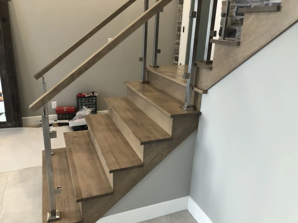 Escalier tournant en bois gris-brun à garde-corps de verre et inox