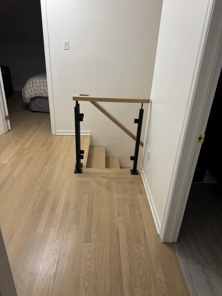 Garde-corps de palier en bois pâle et poteaux métalliques noirs