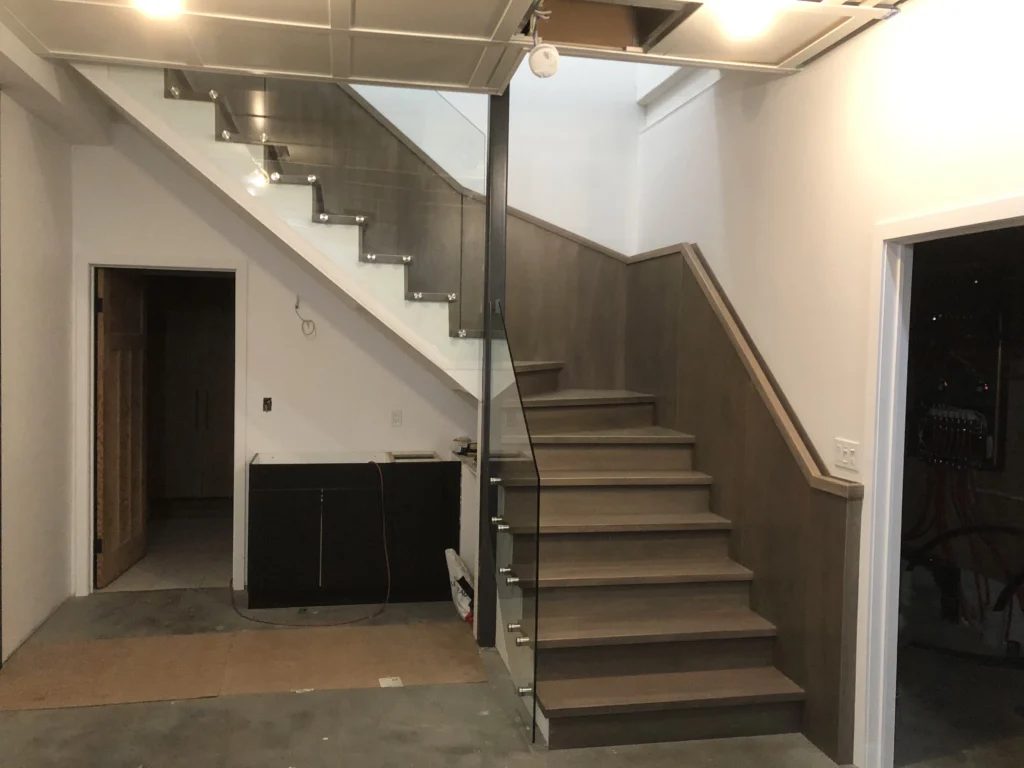 Escalier tournant en bois gris-brun avec garde-corps de verre