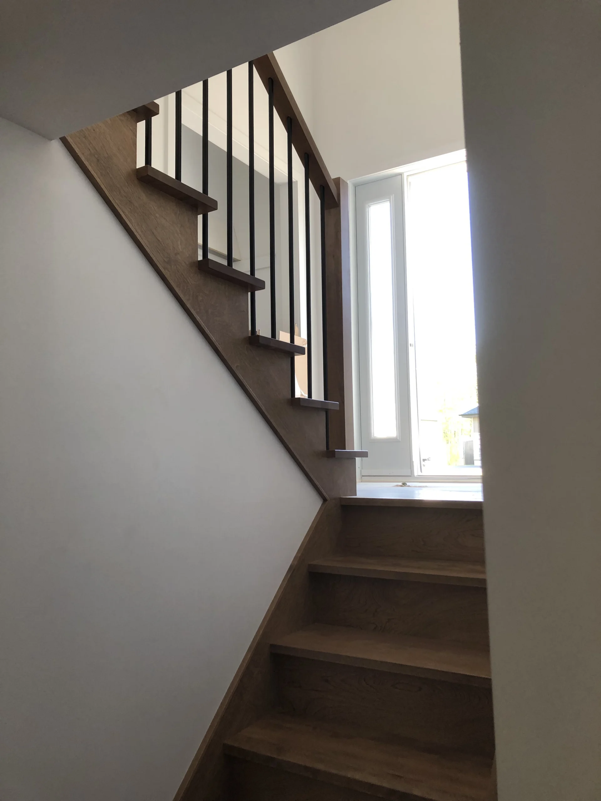 Escalier tournant en bois franc teinté gris-brun à barreaux métalliques noirs — vue principale