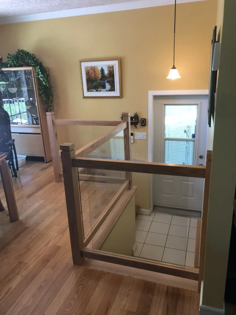 Garde-corps et escalier de demi-niveau en chêne clair avec panneaux de verre encadrés