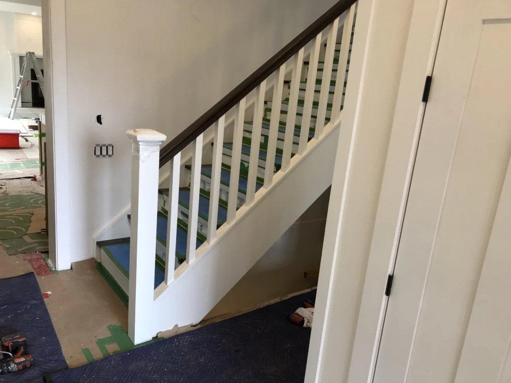 Escalier droit deux tons avec barreaux de bois carrés blancs, contremarches blanches et main courante de bois foncé