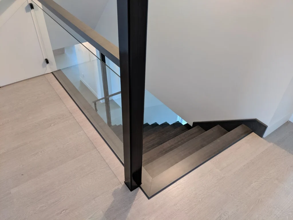 Escalier tournant contemporain avec garde-corps de verre à cadre d&rsquo;acier noir