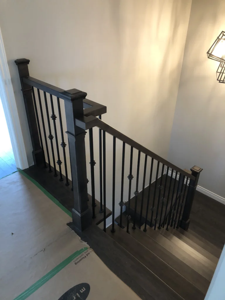 Escalier tournant en érable brun foncé à barreaux de fer forgé