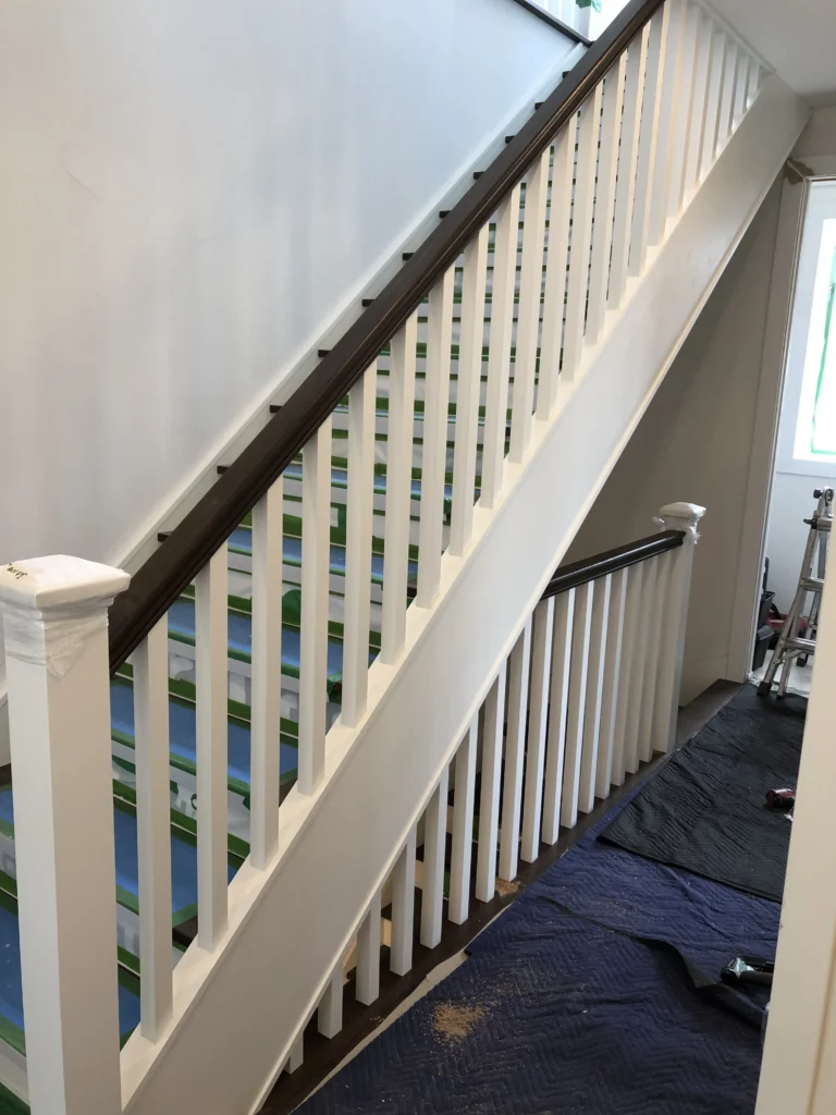 Escalier à barreaux de bois blancs et main courante de bois foncé