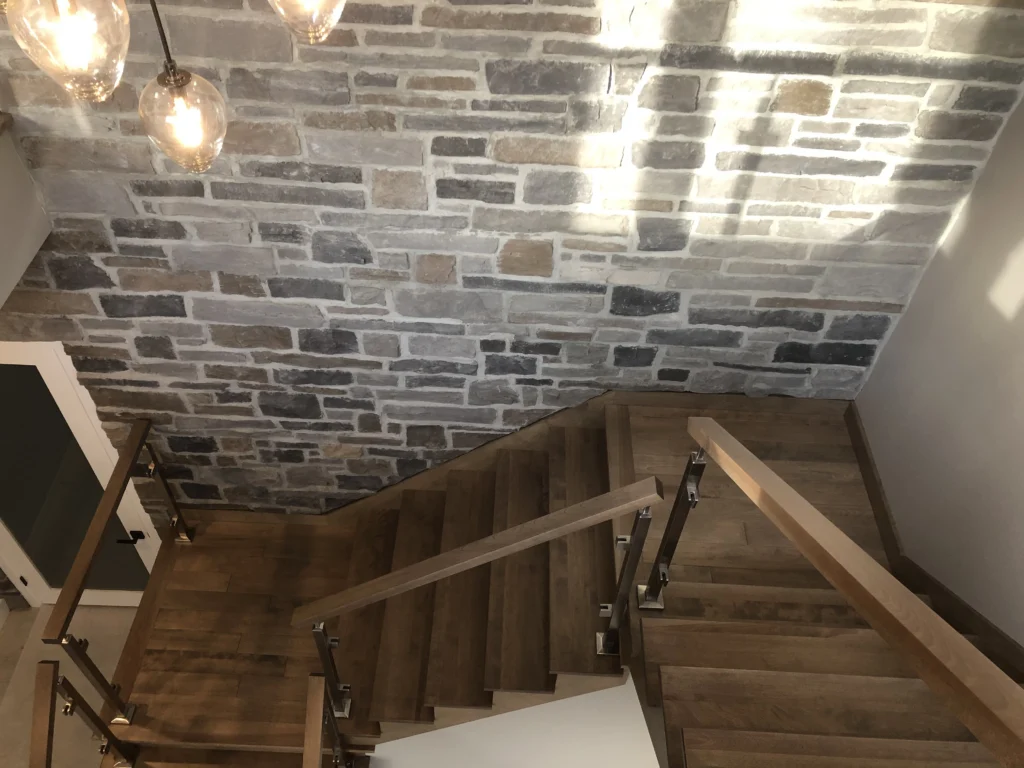 Escalier tournant avec garde-corps de verre et mur de pierre