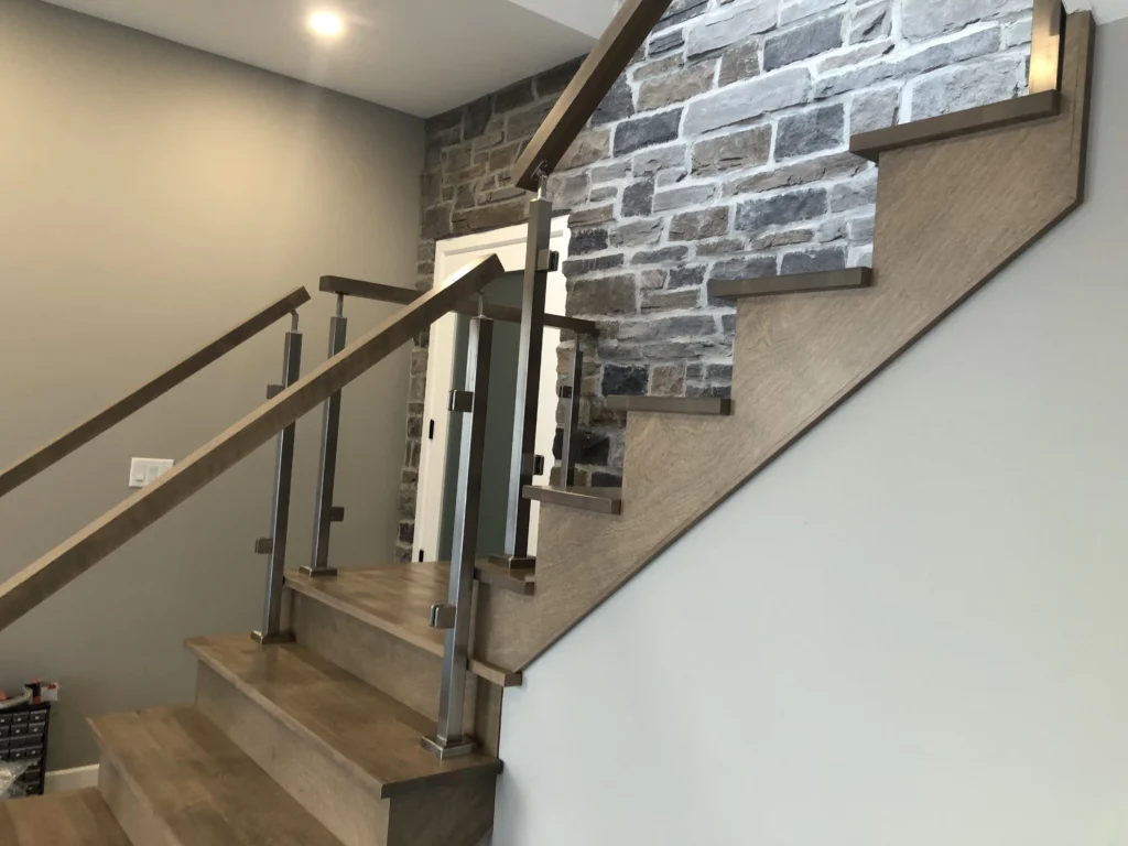 Escalier tournant en bois gris-brun à garde-corps de verre et poteaux métalliques