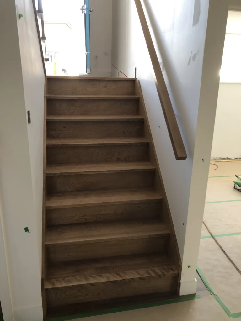 Escalier droit en érable teinté brun à limons fermés, en chantier