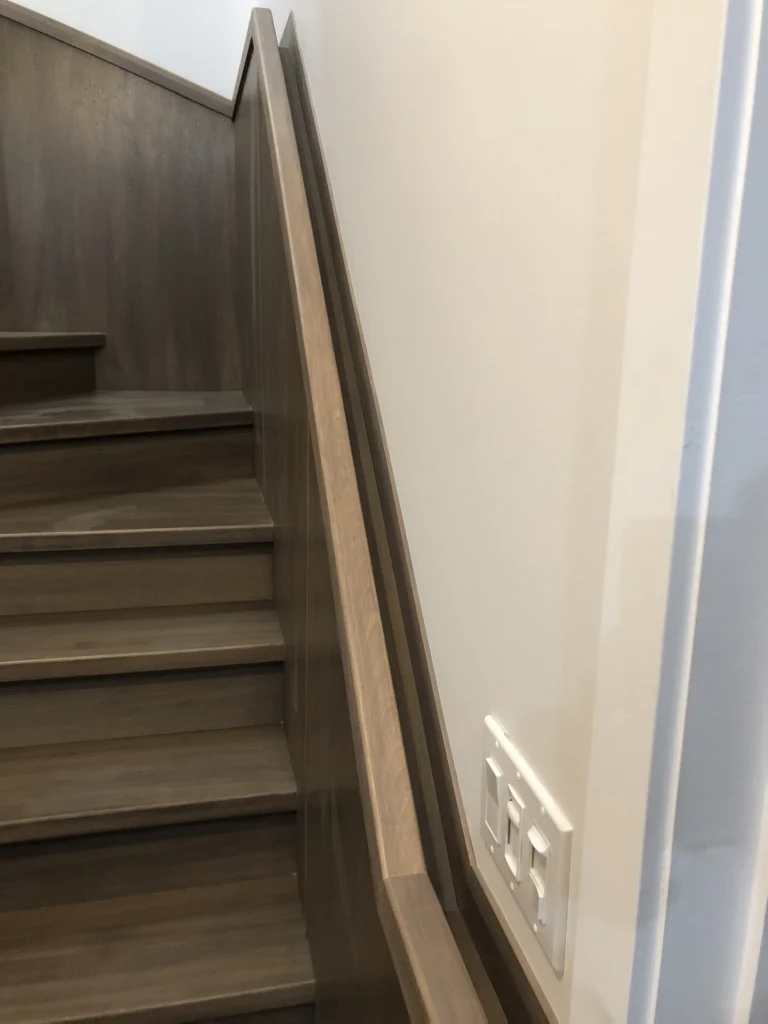 Escalier tournant en bois gris-brun à limons fermés et main courante murale