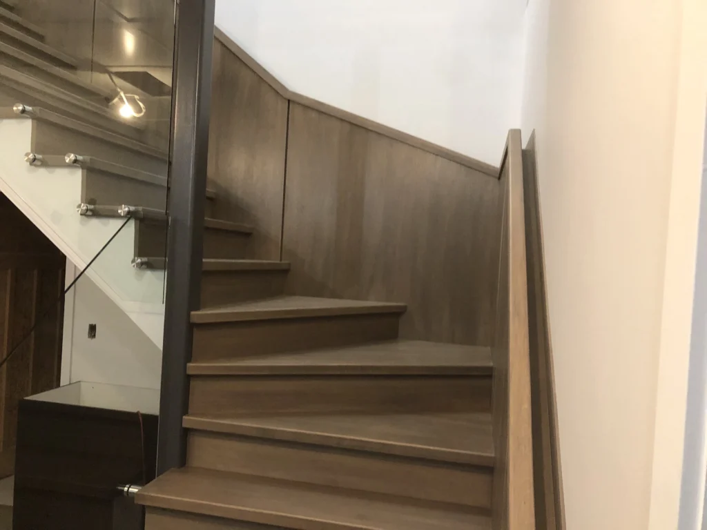 Escalier tournant en bois gris-brun à garde-corps de verre