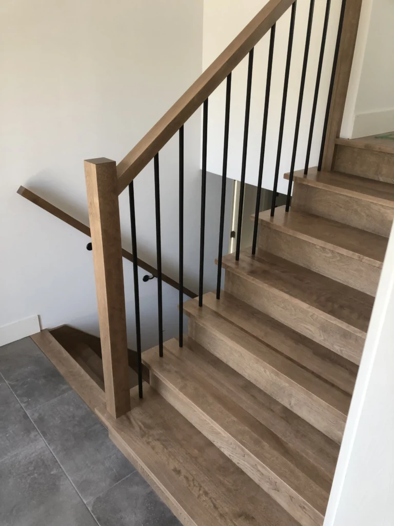 Escalier tournant en bois gris-brun à barreaux métalliques noirs