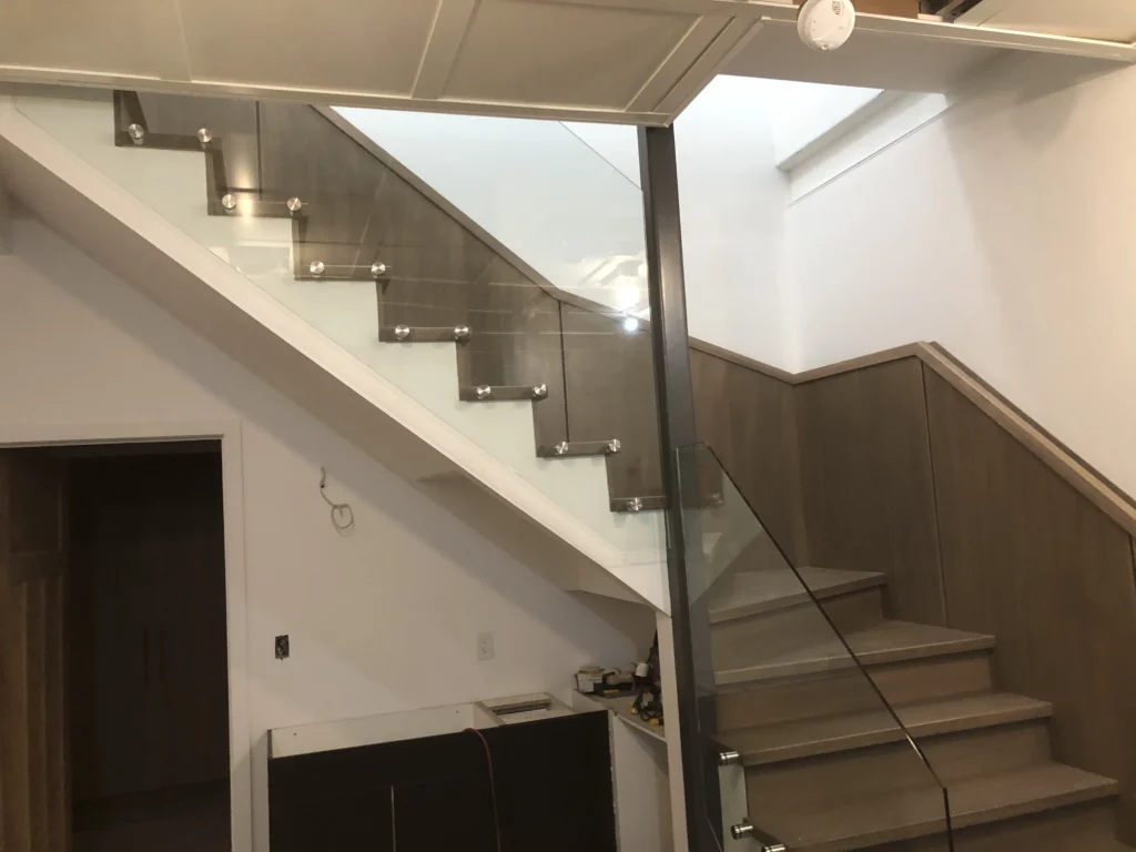 Escalier tournant en bois teinté gris avec garde-corps de verre