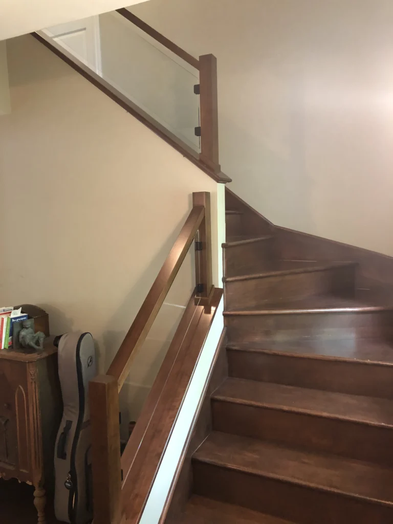 Escalier tournant en bois teinté noyer avec garde-corps de verre