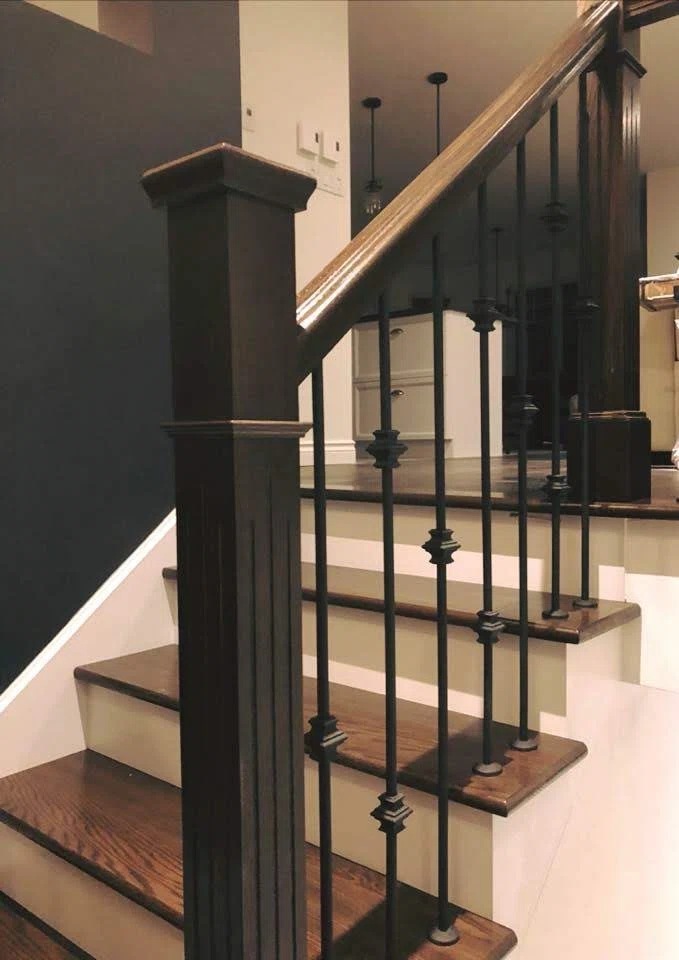 Escalier tournant en chêne foncé à barreaux de fer forgé