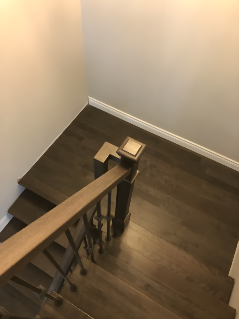 Escalier tournant en bois franc à barreaux métalliques
