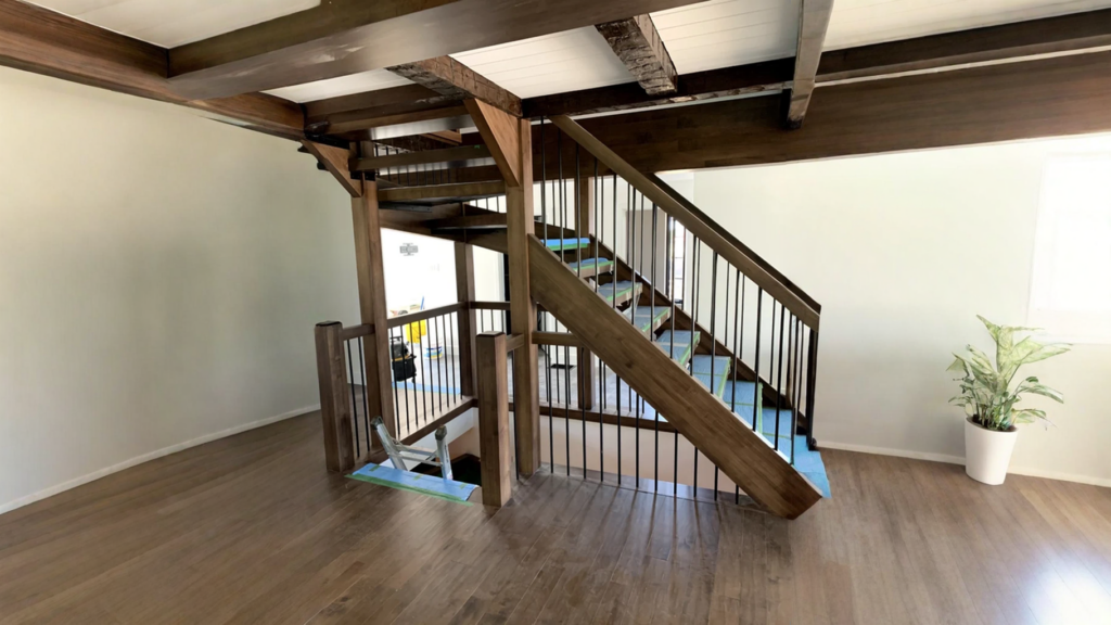 Escalier tournant en bois teinté noyer à barreaux métalliques et poutres apparentes
